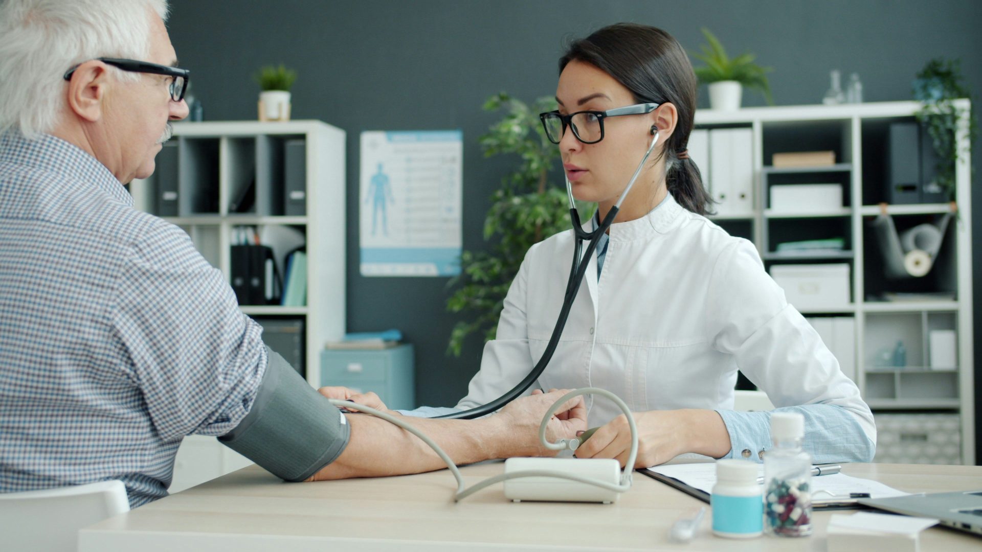 La doctora toma la presión arterial del paciente anciano.